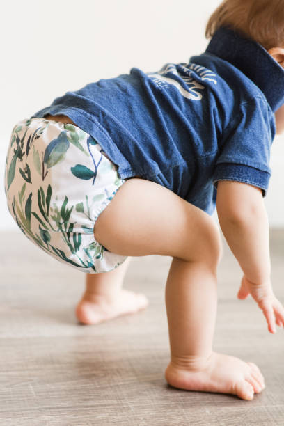 istock A 1-Year-Old Baby Boy Playing on the Floor & Learning to Walk While Wearing Just a Cloth Diaper With a Leaf Pattern & a Blue Shirt 1467744050