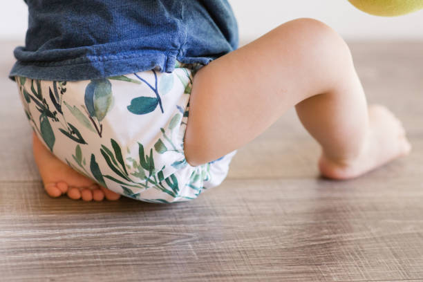 istock A 1-Year-Old Baby Boy Playing on the Floor & Learning to Walk While Wearing Just a Cloth Diaper With a Leaf Pattern & a Blue Shirt 1467744149
