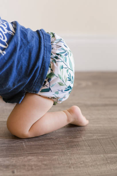 istock A 1-Year-Old Baby Boy Playing on the Floor & Learning to Walk While Wearing Just a Cloth Diaper With a Leaf Pattern & a Blue Shirt 1467744151