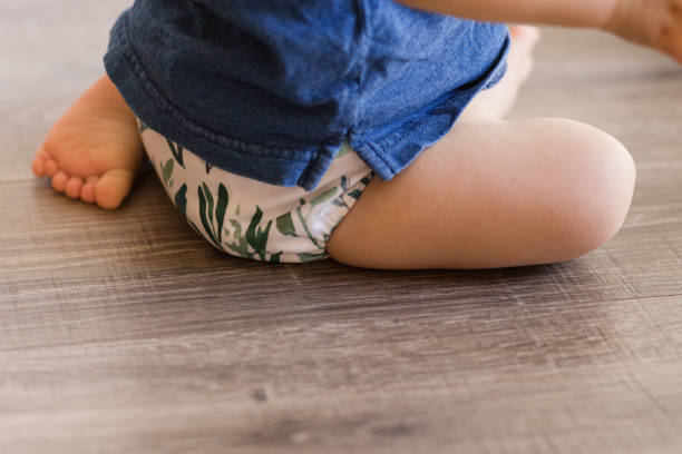 istock A 1-Year-Old Baby Boy Playing on the Floor & Learning to Walk While Wearing Just a Cloth Diaper With a Leaf Pattern & a Blue Shirt 1467744219