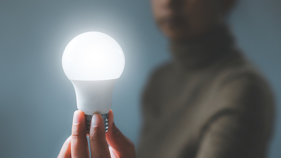 Electric led light bulb in hand. Energy saving and environmentally, Innovation, inspiration, creative solution idea for modern business intelligence technology concept.