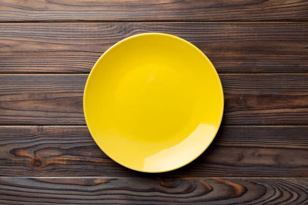 istock Top view of empty yellow plate on wooden background. Empty space for your design 1467749109