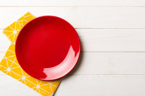 istock Top view on colored background empty round red plate on tablecloth for food. Empty dish on napkin with space for your design 1467749134