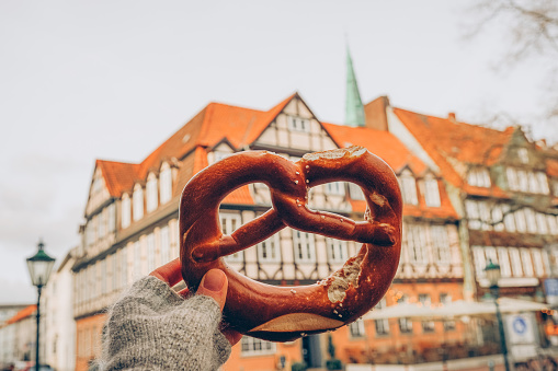 A girl holding a traditional German pretzel on the background of a beautiful architecture or street in Hannover, Lower Saxony, Germany. Local flavor