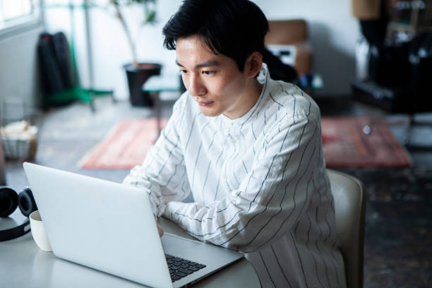 オフィスでノートパソコンで作業する物思いにふける男性 - 勉強　日本人 ストックフォトと画像