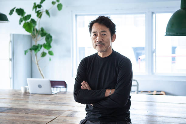 portrait of a man looking at a camera in a modern, stylish office - 50 54 jaar fotos stockfoto's en -beelden