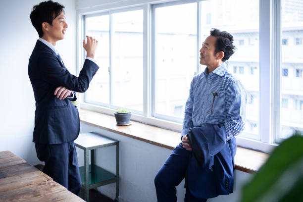 istock Two suited businessmen are having a meeting by an office window 1467754963