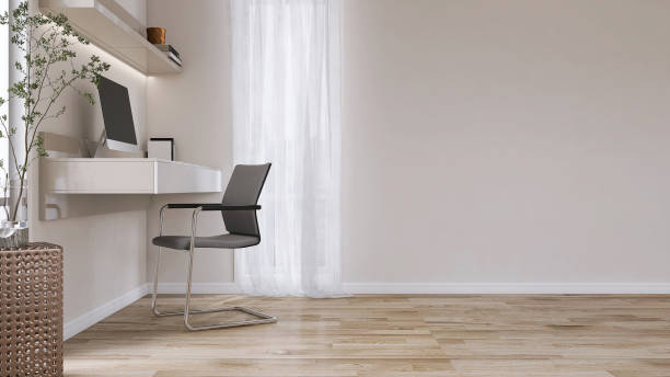 Minimal built in beige working desk with computer, shelf, black steel chair, blank cream wall, parquet floor in sunlight from window with white curtain