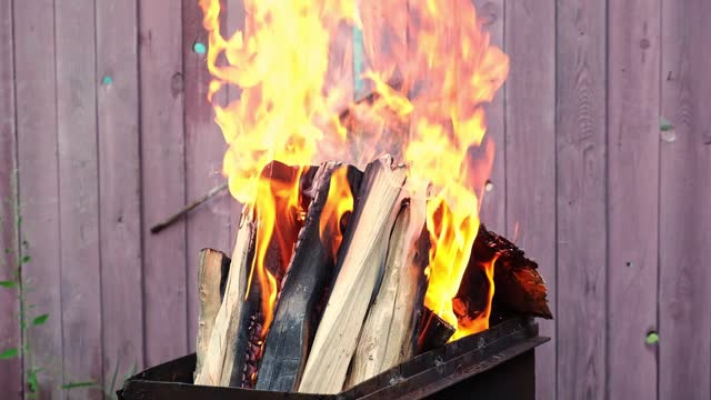 Burning pine logs for coals. Strong flame on the grill. Burning firewood on the grill. The fire is burning on grill.