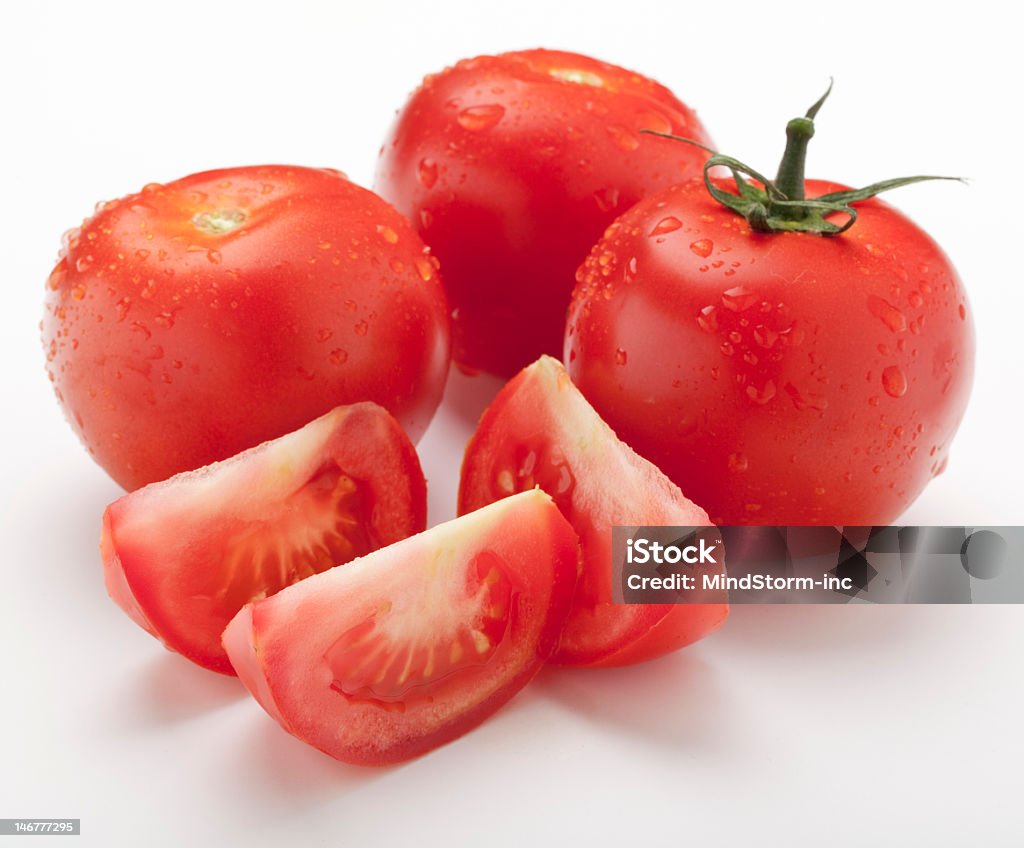 Wet Juicy Tomatoes Three wet juicy tomatoes plus slices on white Close-up Stock Photo