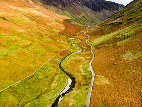 Aerial view of Honister Pass, a mountain pass with a road winding along Gatesgarthdale Beck mountain stream. One of the steepest and highest passes in the region. Cumbria, the Lake District, England.