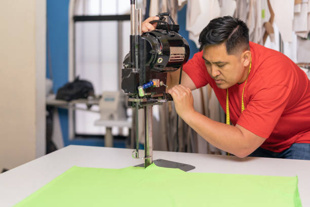 istock Concentrated man using a machine to cut clothes in a textile workshop 1467776707