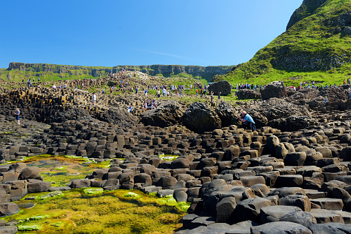 Country Antrim, Northern Ireland - May 28, 2018: Tourists exploring Giants Causeway, an area of hexagonal basalt stones, created by ancient volcanic fissure eruption, County Antrim, Northern Ireland.
