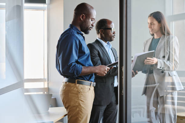 istock Boss talking to his secretary while male employee reading document 1467780463
