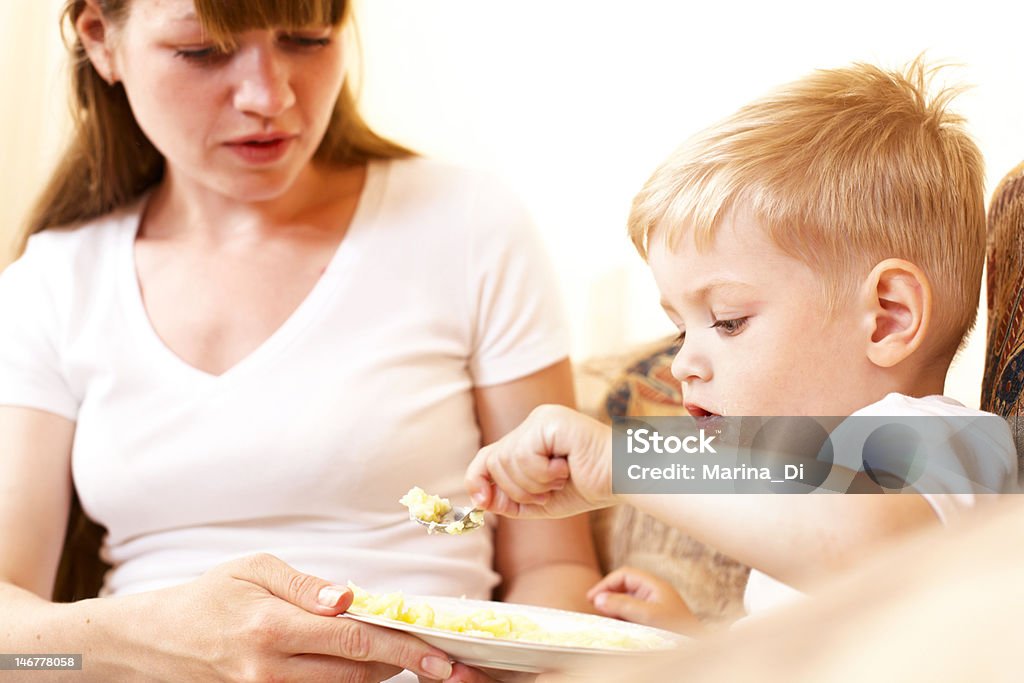 mother feeding her son mother feeding her little son at home; shallow DOF, focus on boys eyes 12-17 Months Stock Photo