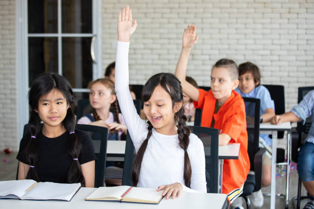 istock Students raising hands while teacher asking them questions in classroom 1467789164