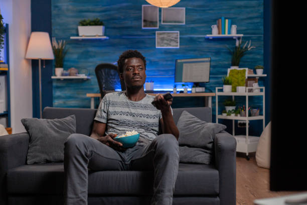 istock African american young man resting on sofa changing channel using remote 1467789336