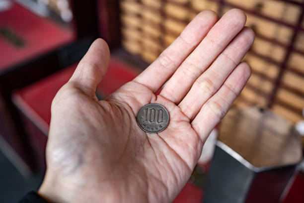 istock 100 yen coin in men hand 1467790510