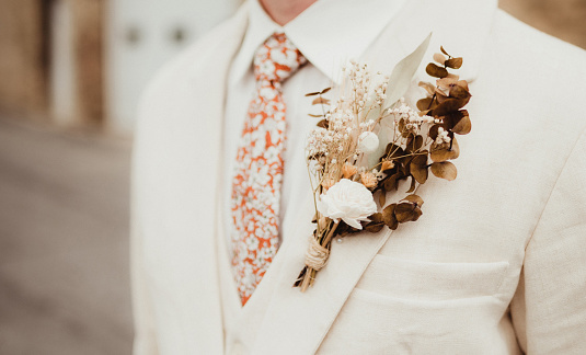 Groom with white suit coat and dried flower boutonniere
