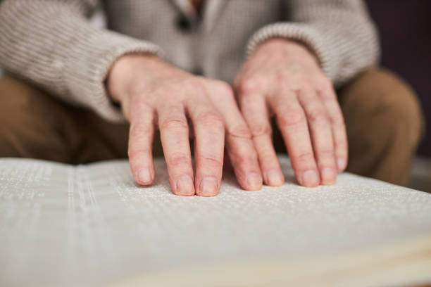 istock Visually impaired man reading book in Braille 1467798422
