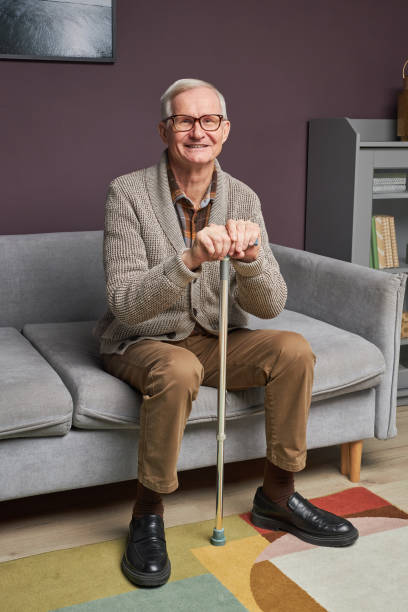 istock Senior man with stick sitting on sofa 1467798494