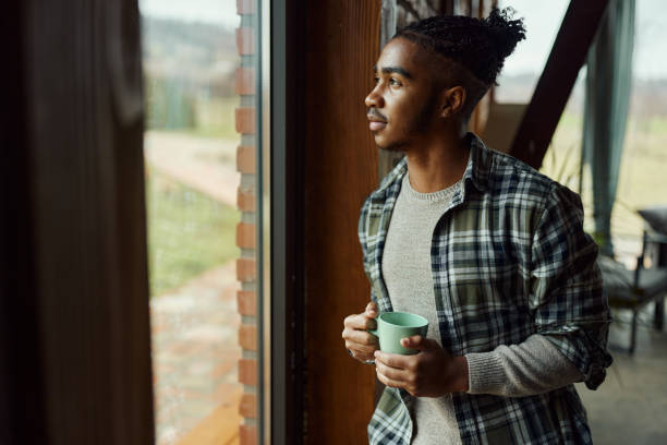 istock Thoughtful black man looking through window from home. 1467798841