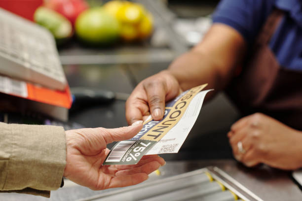 hand of young female cashier passing discount coupon and receit to customer - coupon imagens e fotografias de stock