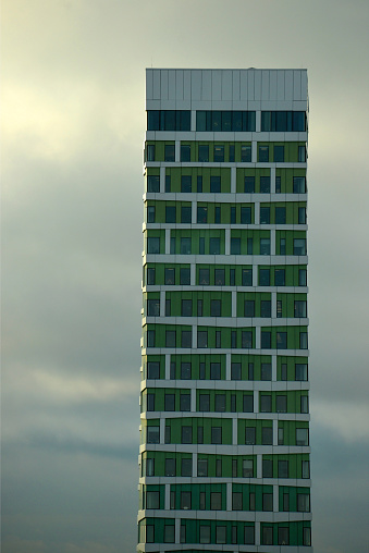 Low angle view of a mordern architectural high rise buliding wih green facade on a sunny morning in Malmö, Sweden