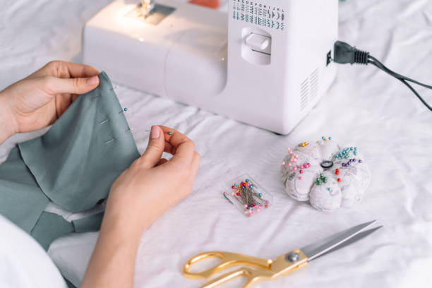 istock Lady fixes fabric with needles in front of a sewing machine 1467810738