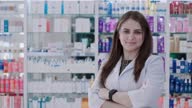 istock Young woman pharmacist poses with crossed arms in front of shelves with medicines 1467812142