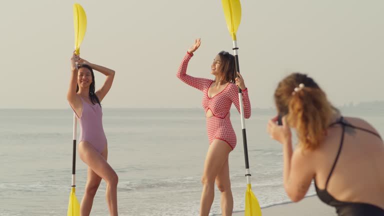 Young Asian female friends take a photo on tropical beach. Healthy active lifestyle and summer vacation.
