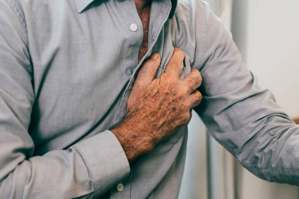 istock Senior man holding hand on chest and suffering from heart problem at home 1467813282