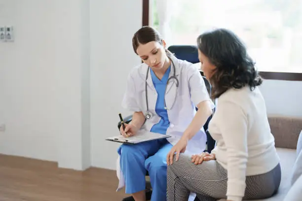 Photo of Portrait of a female doctor talking to a patient with knee pain.