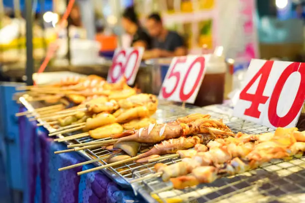 Photo of cooked squid They come in a variety of sizes and are easy to eat. The number 60, 50, 40 is the price of grilled squid stick in Thai Baht.