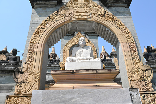 Close-up of a monk statue enshrined at the sandstone pagoda, which is a large sandstone pagoda similar to Borobudur at Wat Pa Kung, Si Somdet District, Roi Et Province, northeast of Thailand.