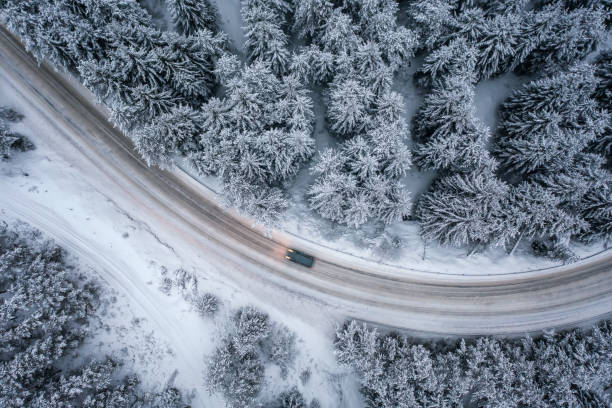 malerischer verschneiter wald mit einem auto auf einer kurvigen straße - drivers point of view country road snowing blizzard stock-fotos und bilder