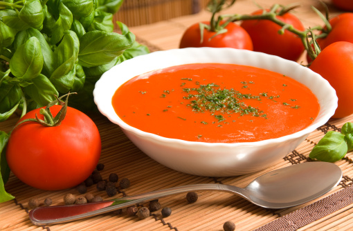 Tomato soup in a bowl with healthy and fresh ingredients and herbs