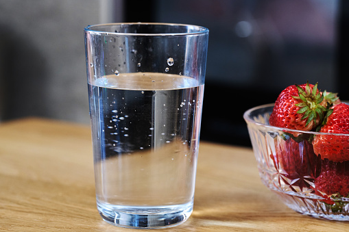 glass of water and fresh strawberries on table