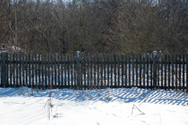 istock A wooden fence with snow in sunlight 1467824910