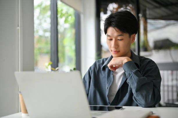 istock Focused Asian man looking at tablet screen, pensively thinking about his marketing project 1467825717
