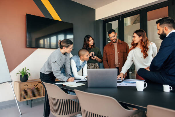 diversi uomini d'affari discutono alcuni rapporti in una sala riunioni - young adult business casual computer foto e immagini stock