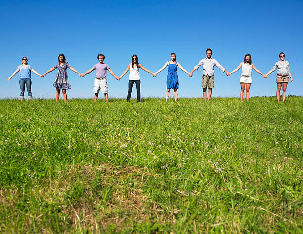 istock Row of eight people holding hands over a grassy hill 146782609