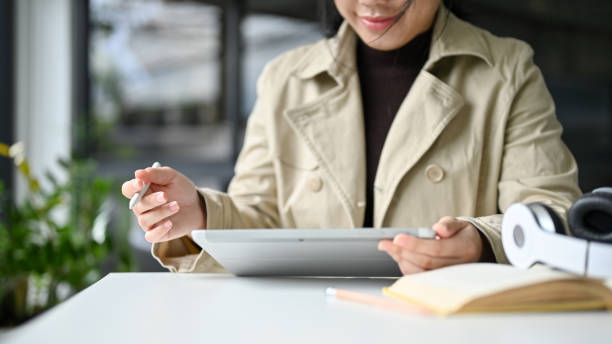 istock Asian woman remote working at the coffee shop or co-working space, using her digital tablet 1467826262