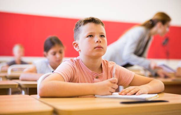 istock Diligent preteen boy studying with classmates in school 1467829932