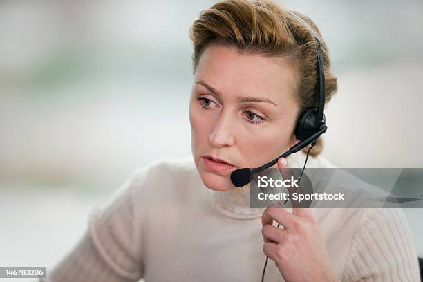 Woman Touching Headset And Staring In Front Of Her Stock Photo - Download Image Now - Customer Service Representative, Hands-free Device, Headset