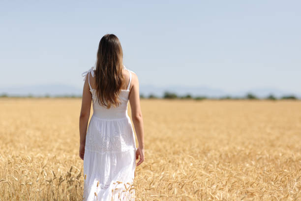 istock Woman in white dress walks in a field 1467834321