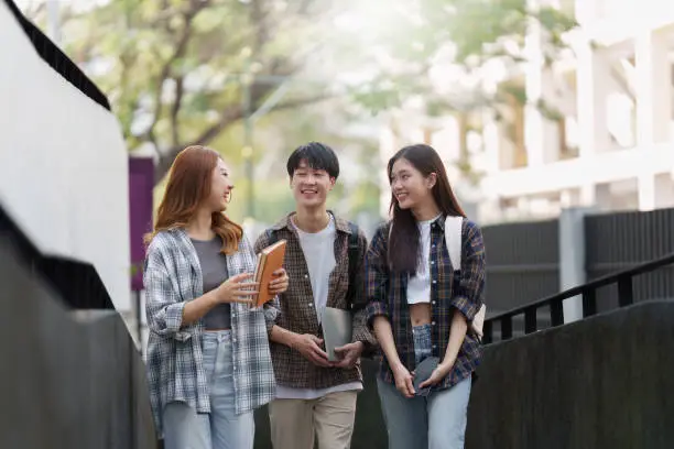 Photo of Group of Young Asian student walking and talking at university before class room. education, back to school concept