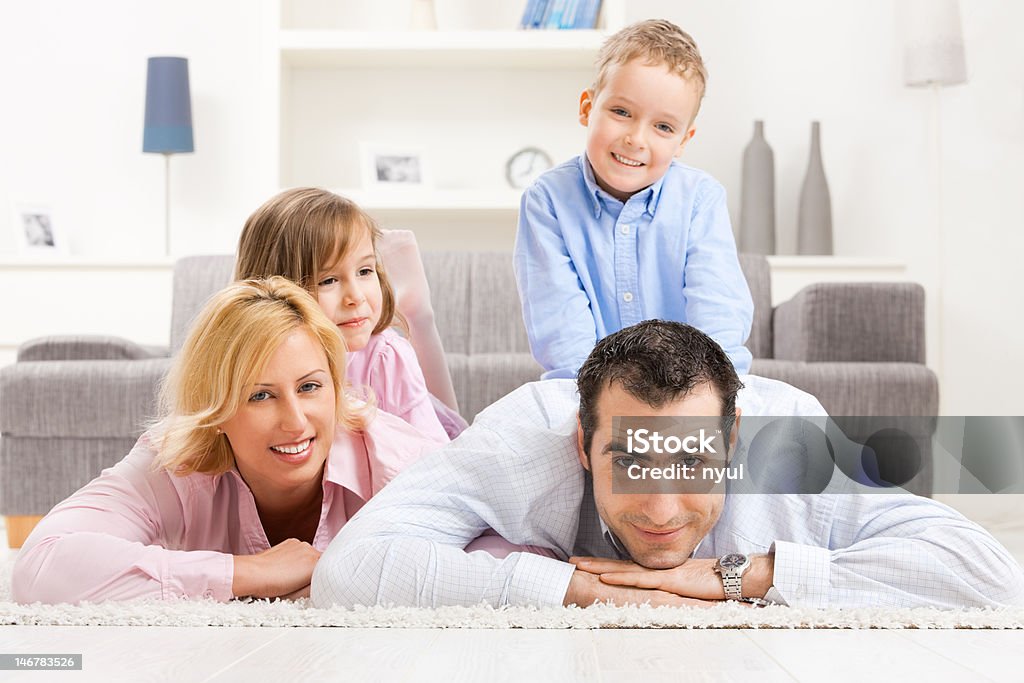 Happy family Portrait of happy family lying together on floor in living room, smiling. Click here for more Family images: 30-34 Years Stock Photo