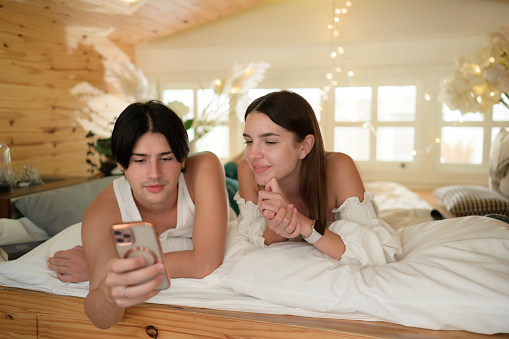 Photo of young teenagers hanging together, in one of the girls bedroom, spending time on social networks