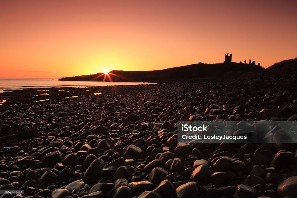 Le Château de Dunstanburgh et lever du soleil sur la côte - Photo de Baie d'Embleton libre de droits